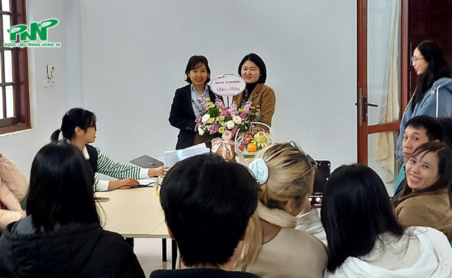 Giảng viên dẫn đoàn tặng hoa cho chị Vũ Minh Phương - giám đốc nhà máy